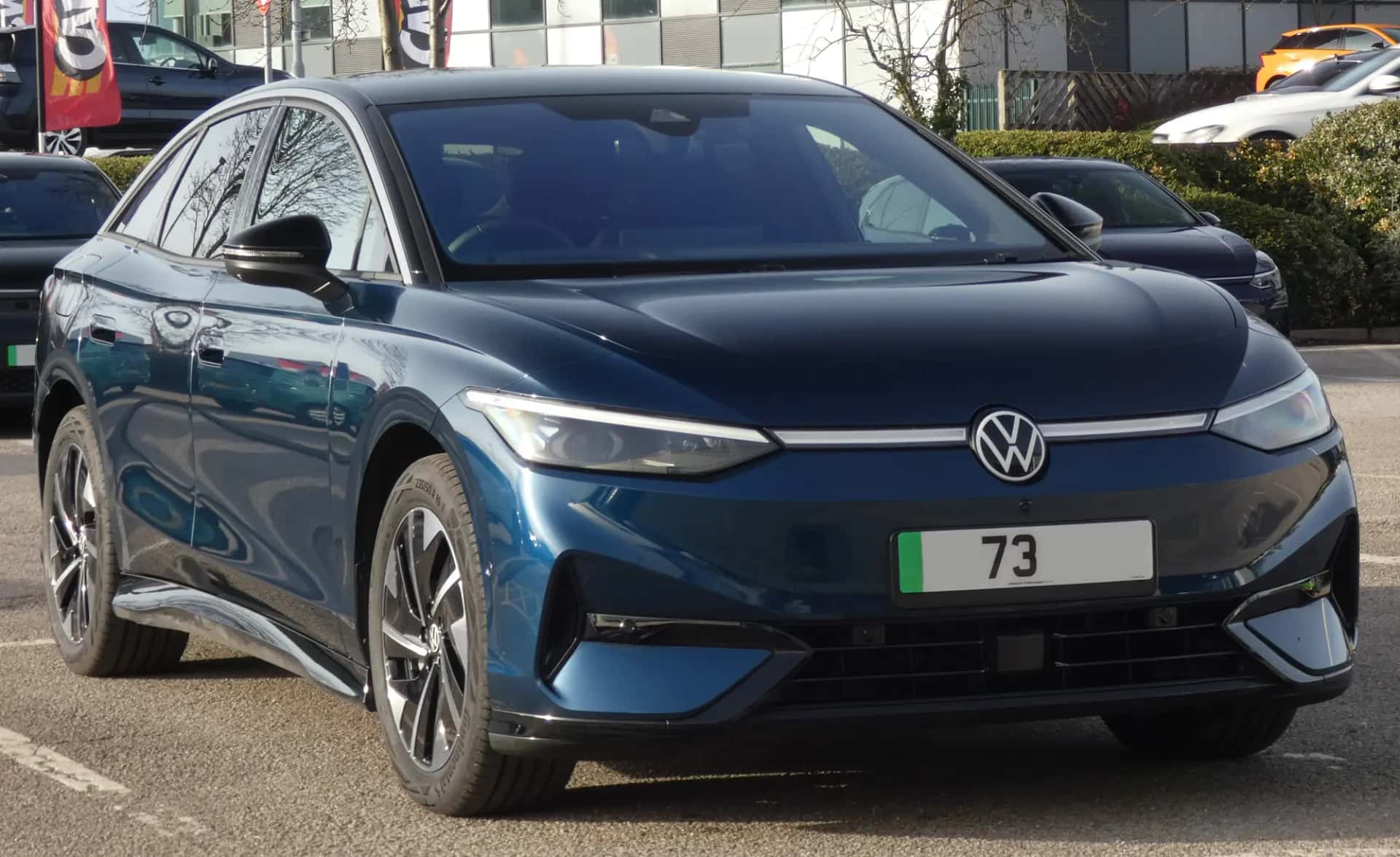 Berline électrique Volkswagen ID.7 bleue vue de trois quarts avant, de face sur un parking