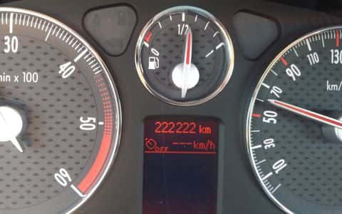 Le tableau de bord d'une voiture affichant un compteur à 222 222 kilomètres