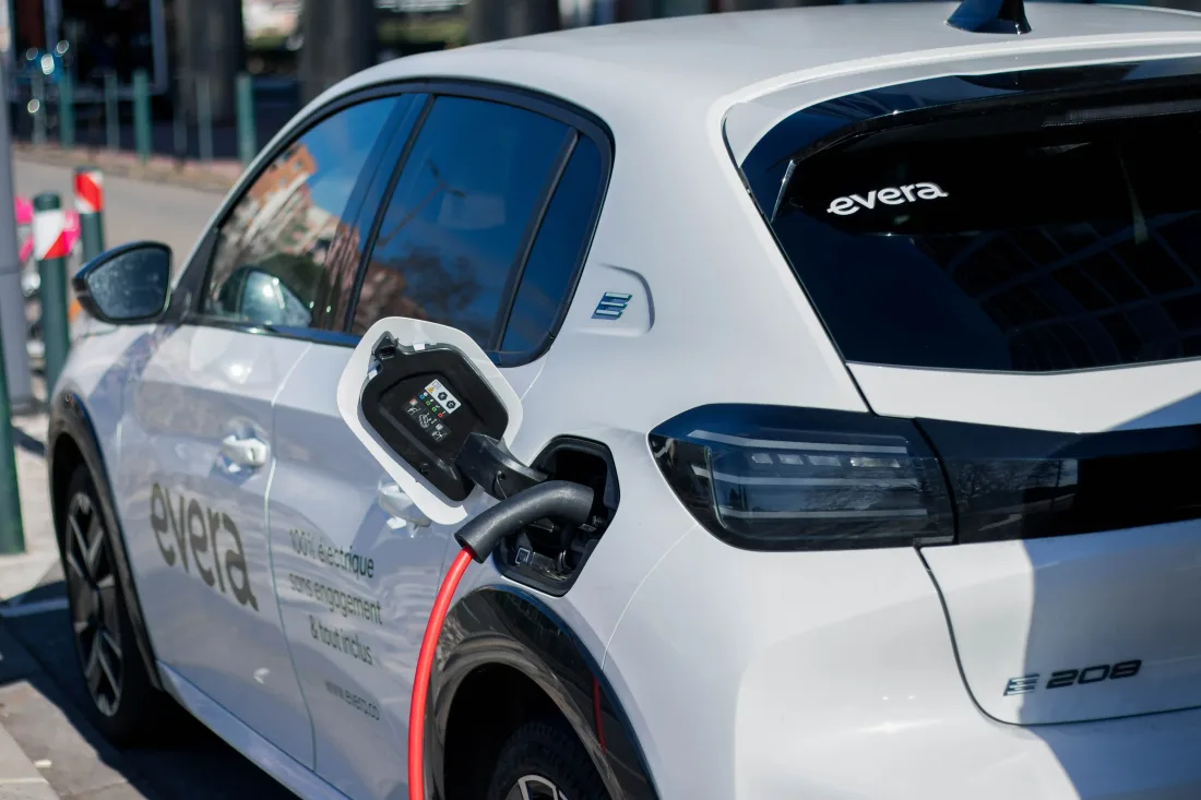 Un utilitaire Peugeot e-208 aux couleurs d'Evera en charge sur une borne de recharge en ville